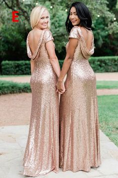 two women in gold dresses holding hands