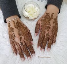 two hands with henna designs on them and a white flower in the middle of each hand