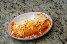 a hot dog covered in cheese and ketchup on a plate