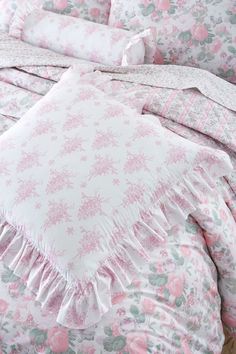 a bed with pink flowers and ruffles on the comforter is shown in this image