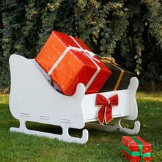 a sleigh with presents on it in the grass next to some christmas gifts