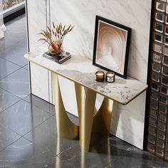 a marble table with two candles on it in front of a white and gold wall