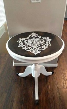 a black and white table with an ornate design on it's top, sitting in front of a wall