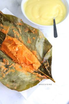 a banana leaf that has some kind of substance on it next to a bowl of sauce