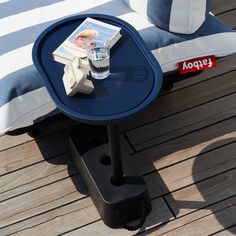 a table with a magazine on it sitting on a wooden deck next to a pillow