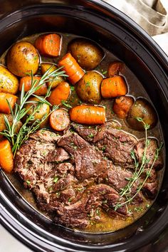 pot roast with carrots and potatoes in a crock pot on a table top