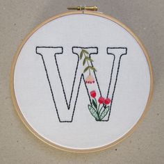 the letter w is made up of letters with flowers and leaves on it, in an embroidery hoop