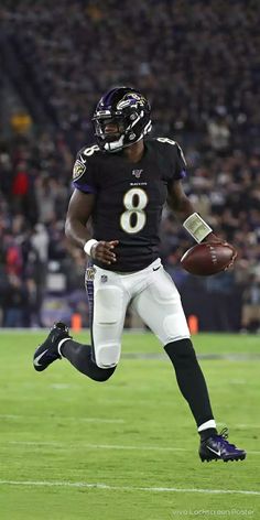 a football player is running with the ball in his hand and wearing a black uniform