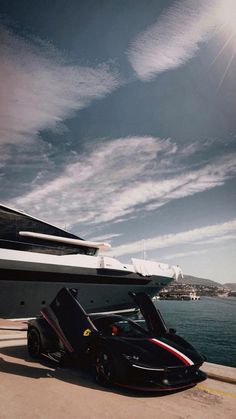 a black sports car parked next to a large boat