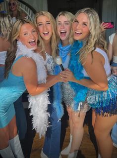 three women in blue and white outfits posing for a photo with one woman holding a microphone