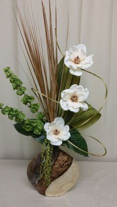 a vase with white flowers and greenery in it