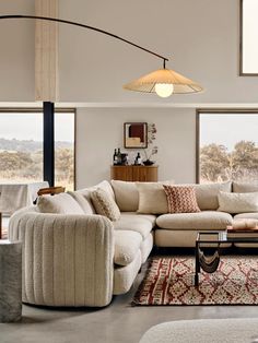 a living room filled with lots of furniture and large windows in the wall behind it