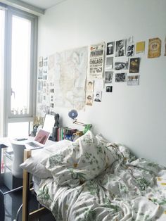 an unmade bed sitting next to a window with pictures on the wall above it