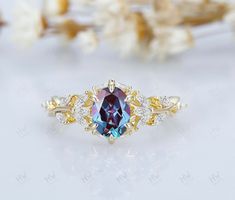 an oval shaped blue and yellow diamond ring with leaves on the side, surrounded by white flowers