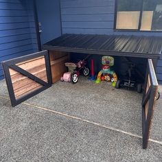 a garage with toys in it on the side of the road next to a blue house