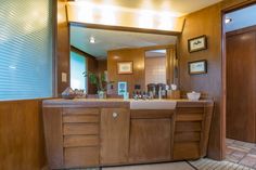 a bathroom with a sink, mirror and tiled flooring in front of the door