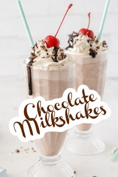 two glasses filled with chocolate milkshakes and topped with whipped cream, sprinkles and cherries