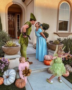 two children and an adult are dressed up as tinkerbells in front of a house