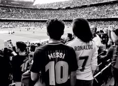 two people standing in front of a crowd at a soccer game with their backs to the camera