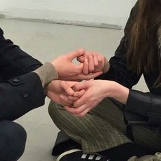 three people sitting on the floor holding hands together