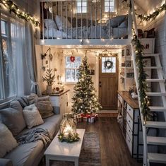 a living room filled with lots of furniture and christmas lights on the stairs above it