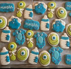 decorated cookies with blue and green frosting are arranged on a baking sheet in the shape of monsters