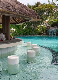 an outdoor pool with white stools and water features