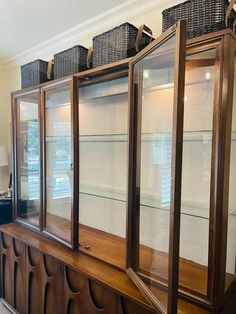 a display case with glass doors and wicker baskets on top in a living room