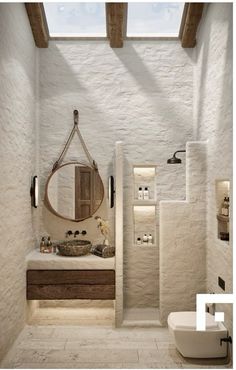 a bathroom with a sink, mirror and toilet in the corner next to an open skylight