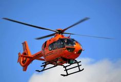 an orange helicopter is flying through the air