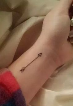 a woman's arm with an arrow tattoo on it