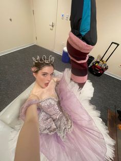 a woman laying on the floor wearing a dress and tiara with her feet up