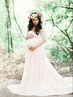 a pregnant woman wearing a flower crown standing in the woods