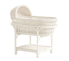 a white wicker baby bassinet sitting on top of a table