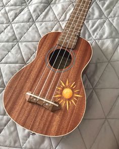 the ukulele is made out of wood and has an orange sun on it