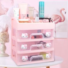 a pink plastic drawer with hello kitty items in it and a flamingo behind it