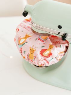 a close up of an electric mixer on a white table with a pink cloth covering it