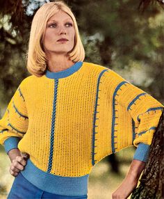 a woman standing next to a tree wearing a yellow sweater