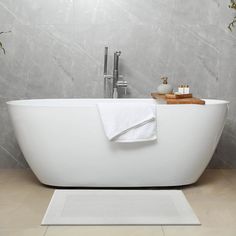 a white bath tub sitting in a bathroom next to a wooden tray with flowers on it