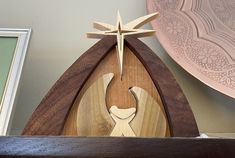 a wooden nativity piece on top of a shelf next to a framed photograph and other decorations