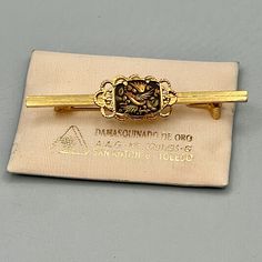 "Vintage 18K/24K Gold Inlay Damascene Bar Pin Made by Alca Jewelry, Toledo Spain There is no damage or tarnish.  This is much prettier in person.  Since the pin itself is not marked, I am guessing the bar and setting is gold tone. The Black steel with the gold thread inlay is what is actually gold.  \"Toledo is renowned for its damasquinados, or damascene handicrafts and costume jewelry. Damascening is the Moorish art of inlaying gold or silver threads into black steel in a decorative pattern\" Photo props are not for sale. Please see the photos for the best description. Ask if you would like more pictures or information. We want you to know exactly what you are getting before it arrives at your door. If you are buying more than one item from my shop, I will combine shipping and refund the Gold Threads, Original Jewelry, Black Steel, Etsy Items, Collectable Items, Costume Jewelry, Halloween Shopping, Gold Tones, Vintage Jewelry