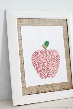 an apple made out of candy canes is displayed in a white frame on a shelf