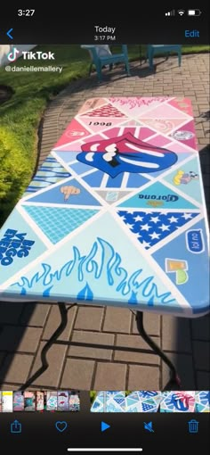 a table that has been painted with different colors and designs on it, sitting in the middle of a sidewalk