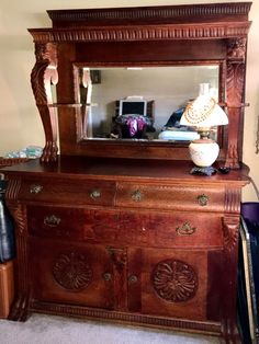 a wooden dresser with a mirror on top of it next to a lamp and other items