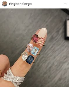 a woman's hand with different colored stones on it and rings around her finger