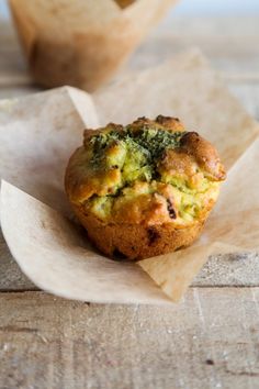 a muffin with broccoli sitting on top of a piece of parchment paper