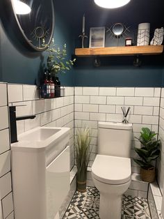 a white toilet sitting in a bathroom next to a sink under a mirror and potted plant