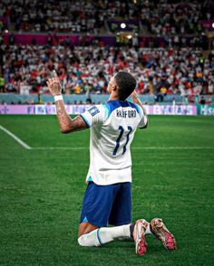 a soccer player sitting on the ground with his hands in the air and one hand up to his face