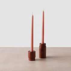 two wooden candlesticks sitting next to each other on top of a cement surface