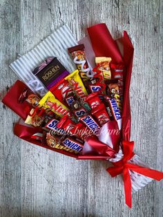 a basket filled with assorted candy on top of a wooden table next to a red ribbon